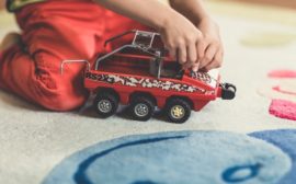 Enfant noir jouant avec un jouet rouge.