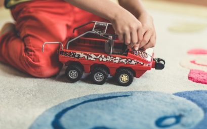 Enfant noir jouant avec un jouet rouge.