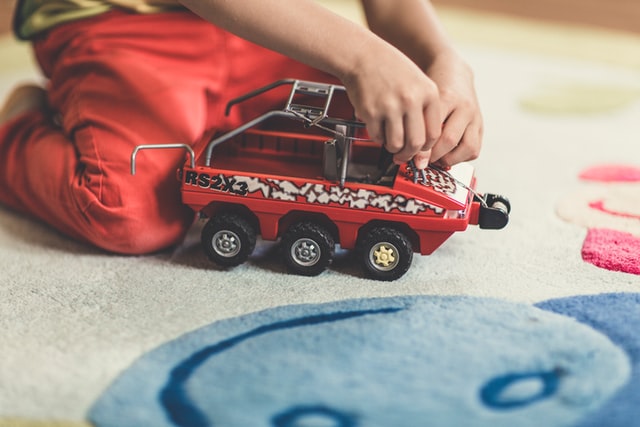 Enfant noir jouant avec un jouet rouge.